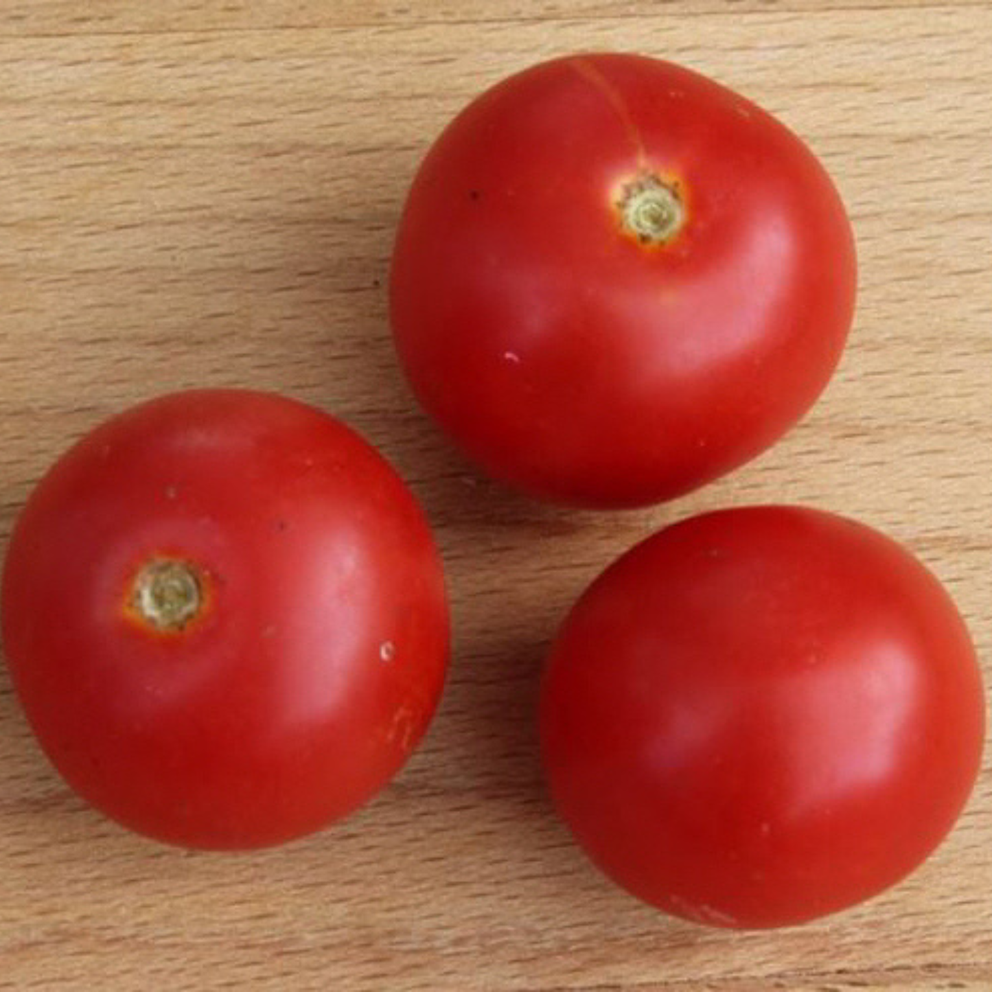 Close-up of ripe Mohammed micro dwarf cherry tomatoes displayed on a wooden table.