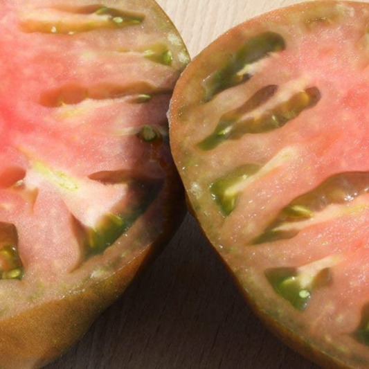 Two sliced Blackberry heirloom tomatoes displaying rich pink flesh and distinctive green seed cavities.