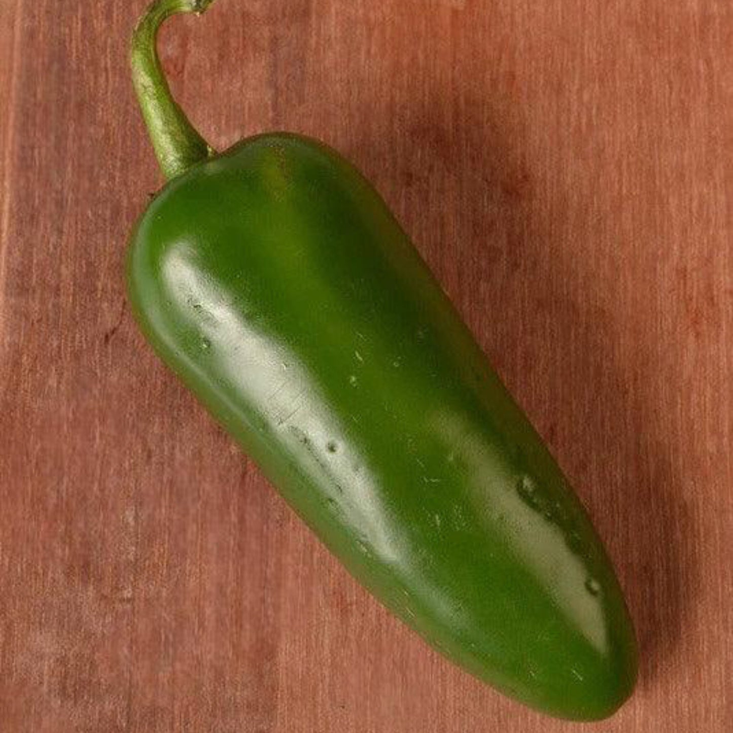 Harvested green Jalapeño pepper on a wooden surface