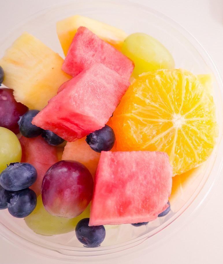 Freshly sliced Sugar Baby watermelon with sweet, juicy red flesh served alongside assorted fresh fruit, perfect for summer snacking and fruit salads.